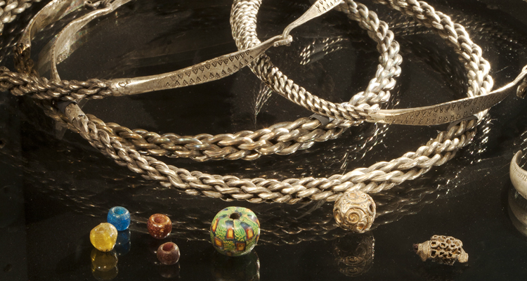 Halsringar i silver och färggranna glaspärlor från järnåldern.